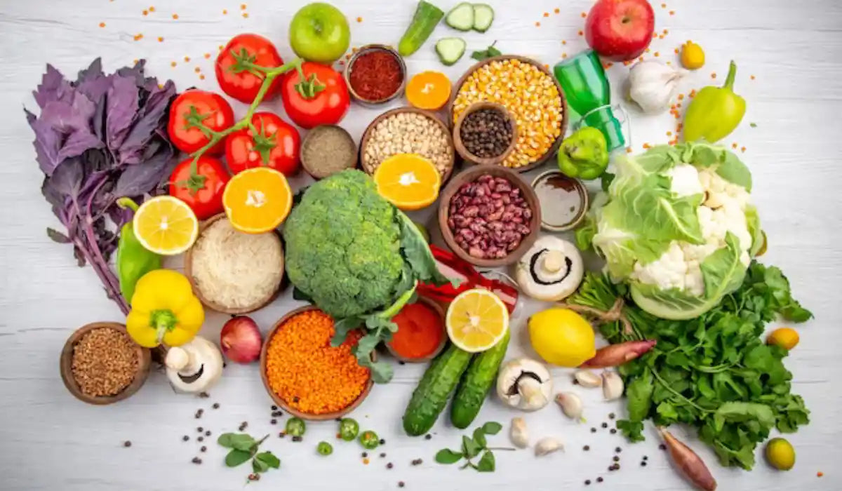 Colorful spread of fresh vegetables, fruit, beans, lentils and grains on a white wooden table