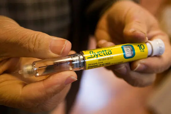 Close-up of hands holding a yellow Byetta exenatide injection pen