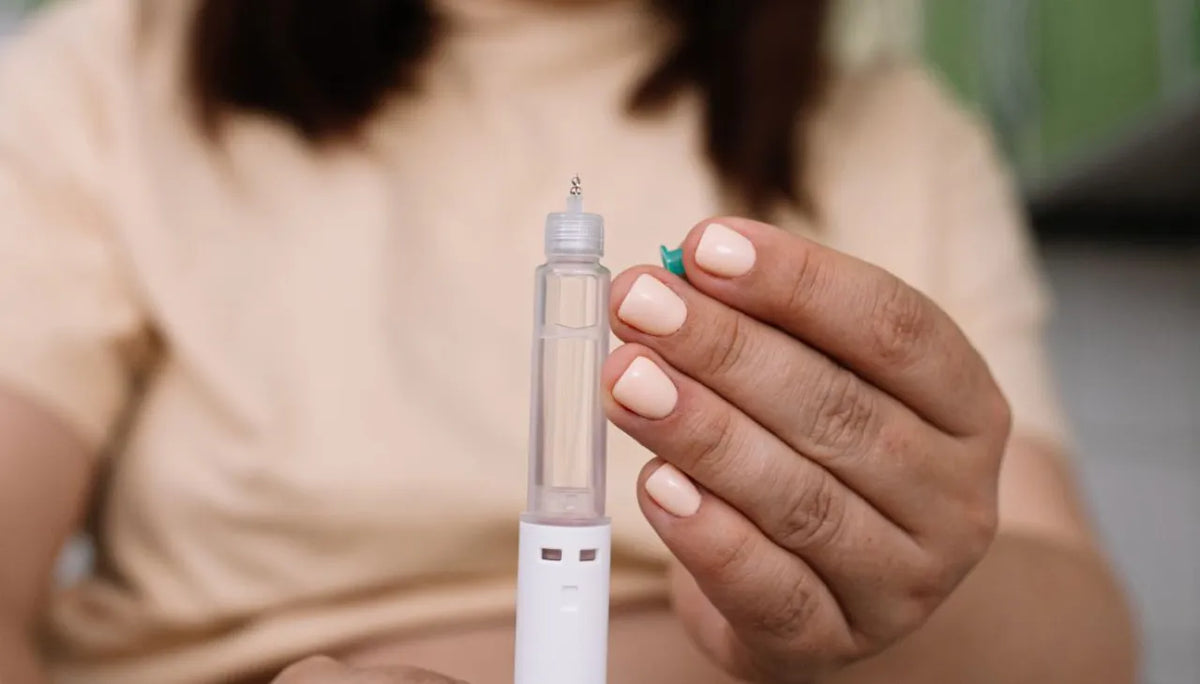 Woman holding a white injection pen upright between her fingers
