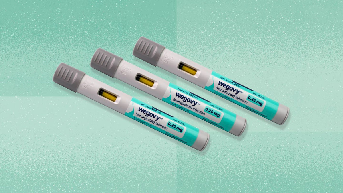 Three Wegovy injection pens laid diagonally on a mint green background