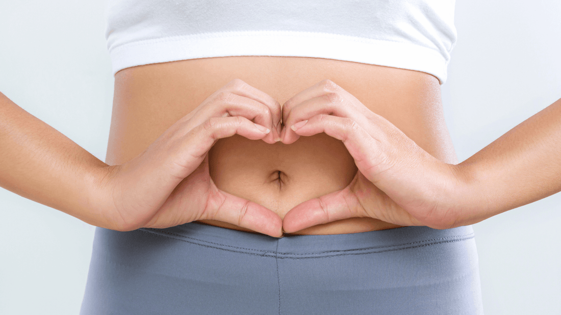 Woman forming a heart shape with her hands over her bare stomach