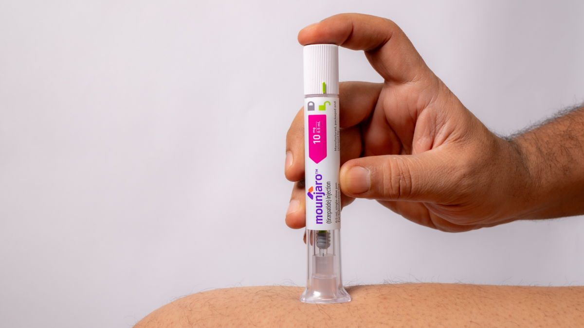 Hand pressing a Mounjaro tirzepatide autoinjector pen against the skin
