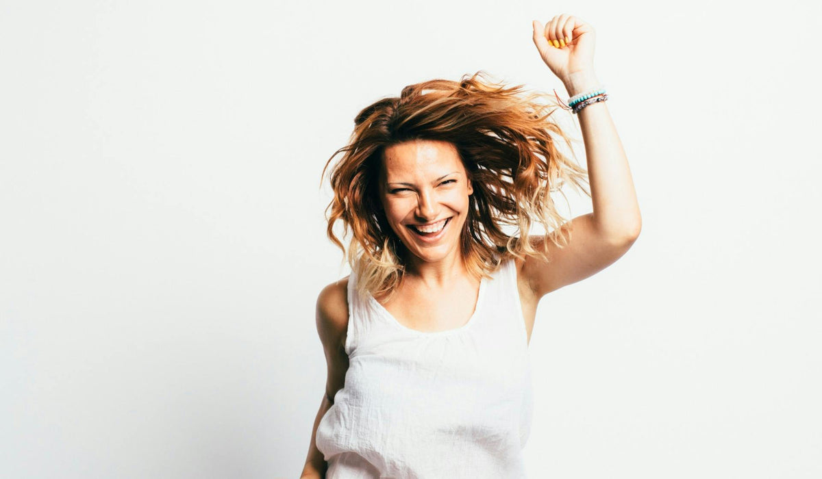 Smiling woman with curly hair raising her fist in celebration against a white background