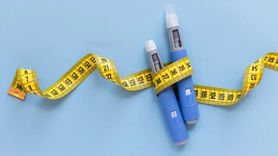 Two blue injection pens wrapped in a yellow measuring tape on a light blue background