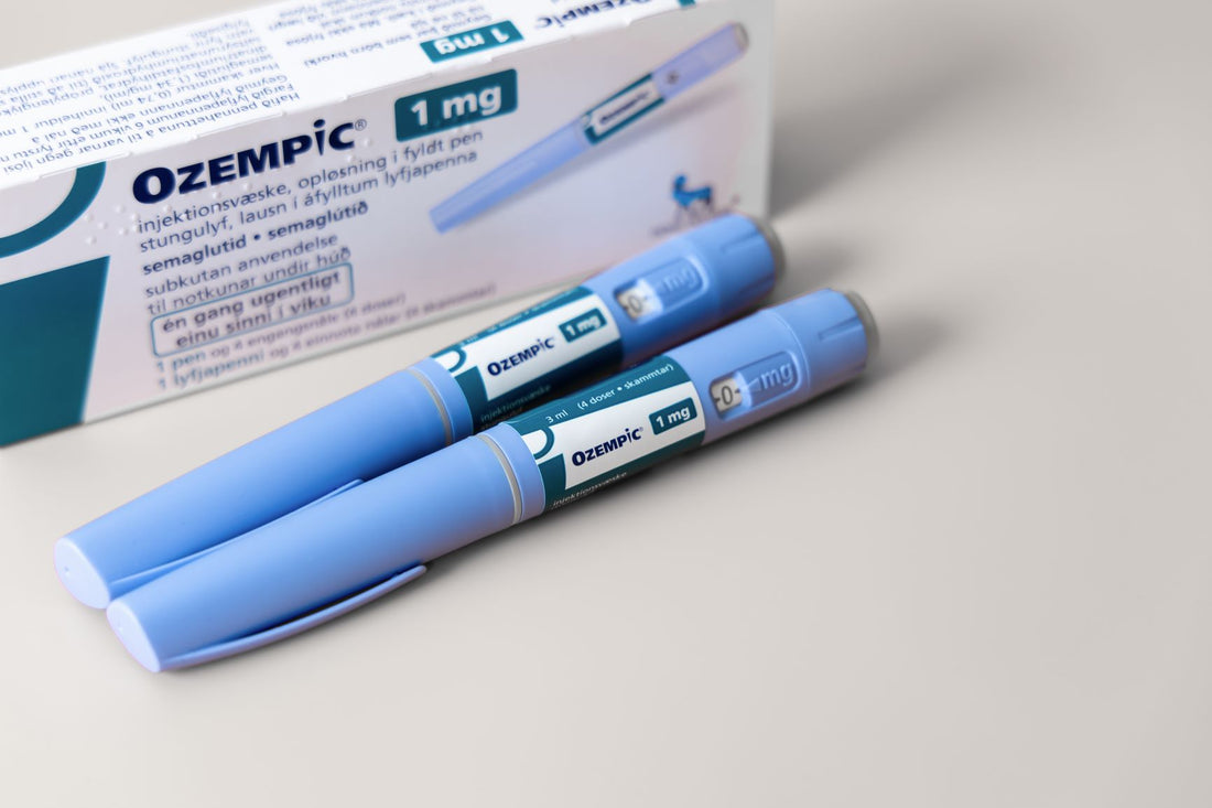 Two blue GLP-1 injection pens lying beside their prescription box on a gray surface