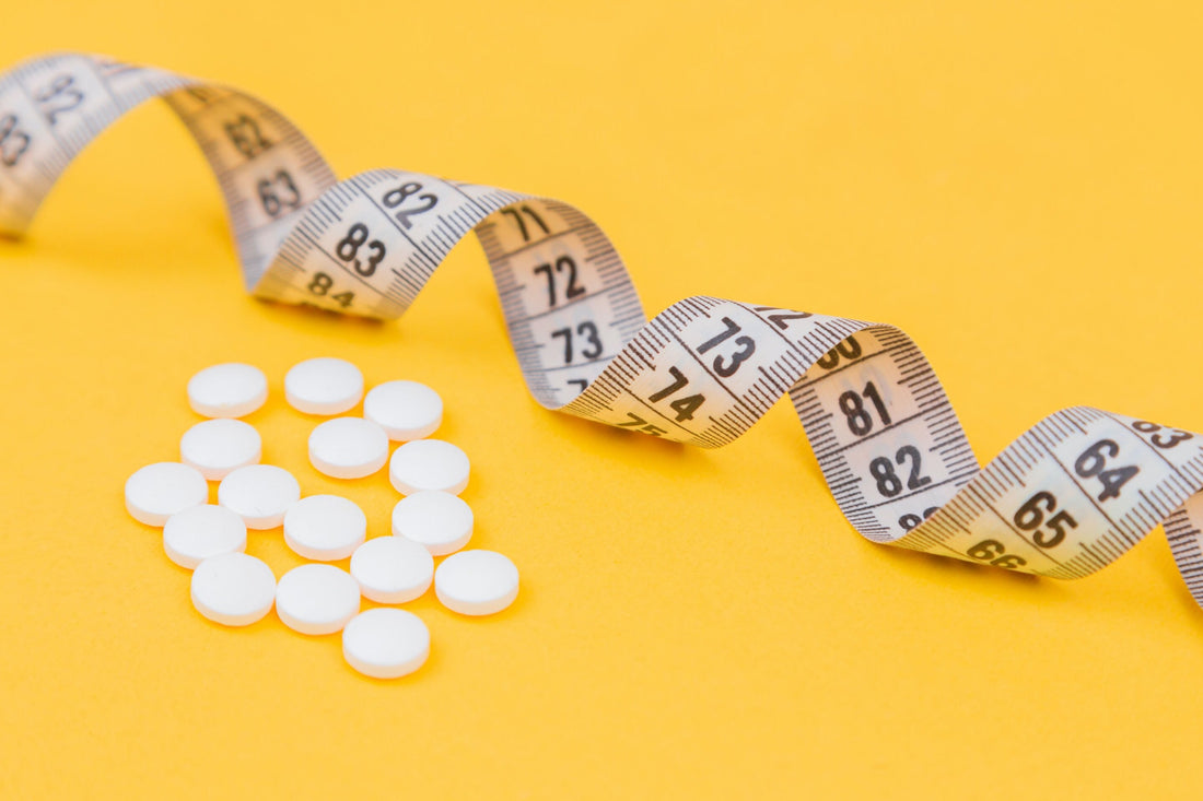 White tablets scattered beside a measuring tape on a bright yellow background