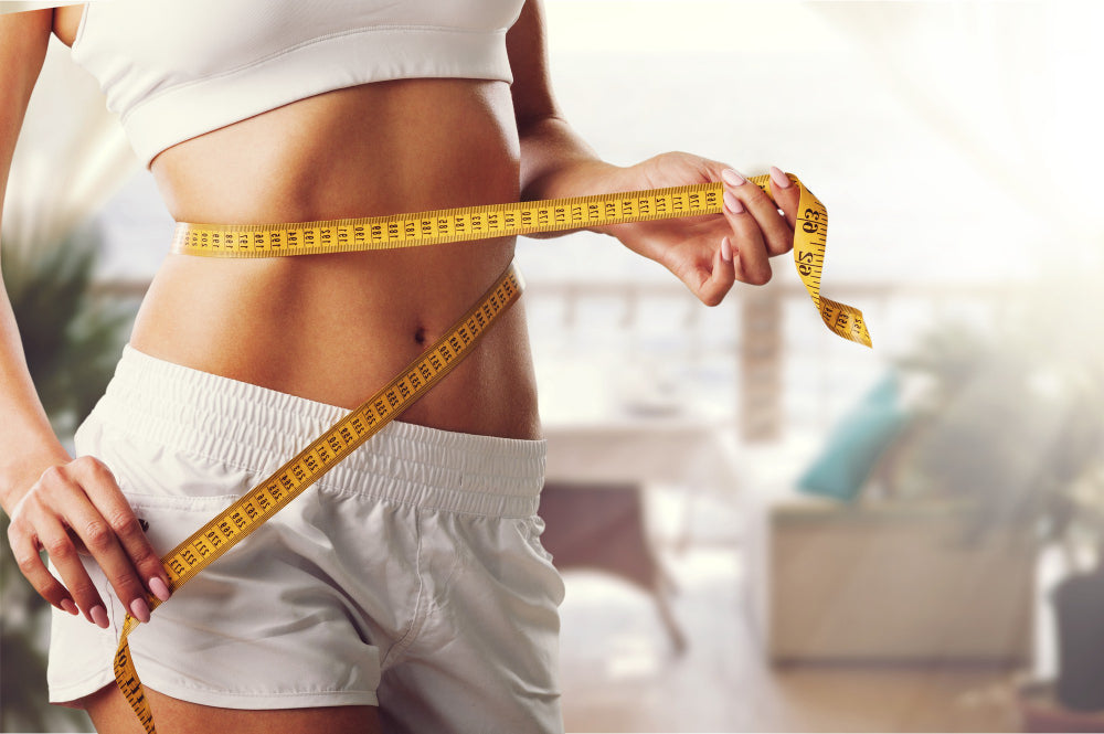 Woman measuring her waist with a tape measure