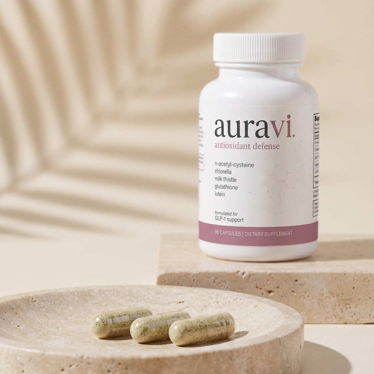 Antioxidant Defense capsules on a travertine dish beside the bottle