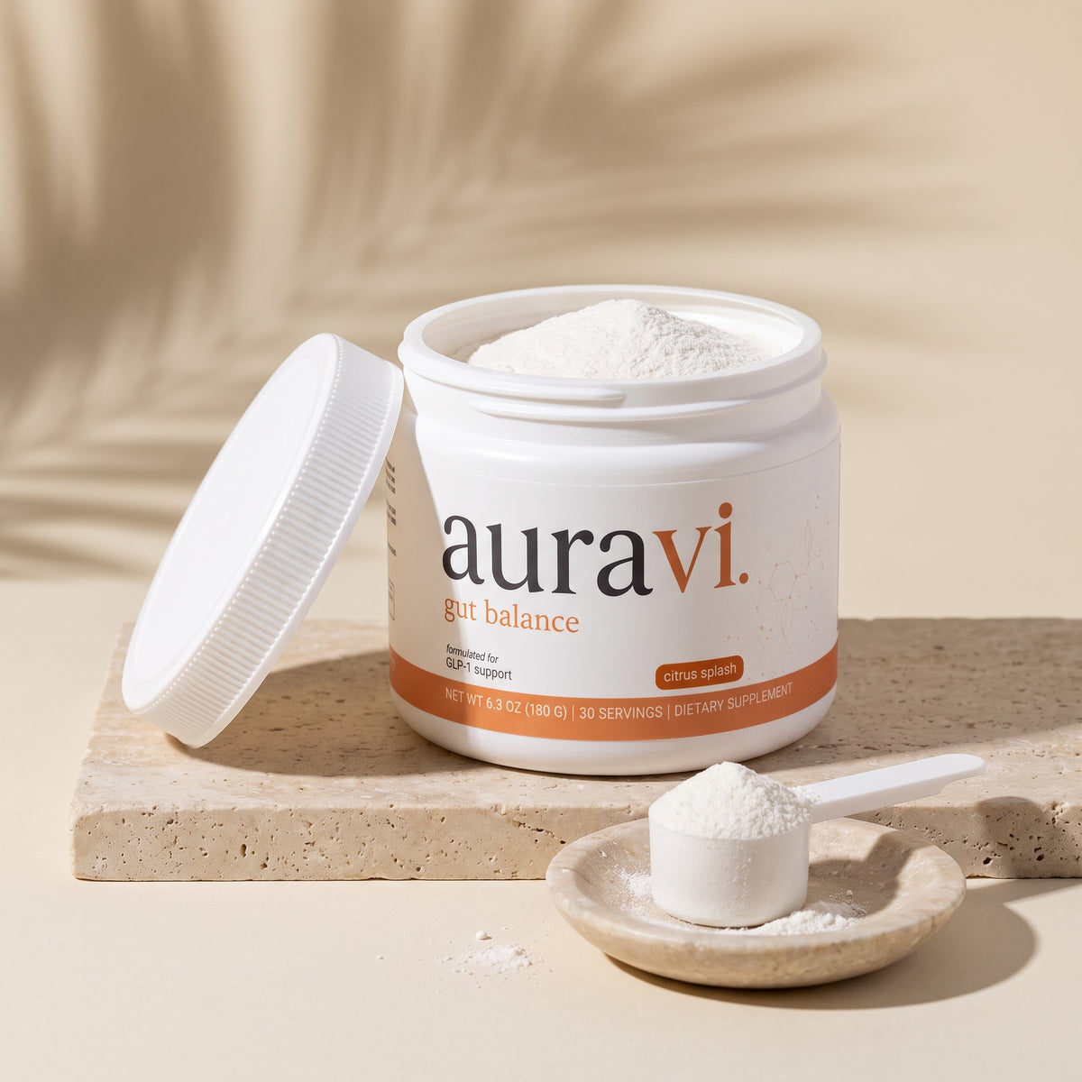 Open tub of Gut Balance with a scoop of white powder on travertine