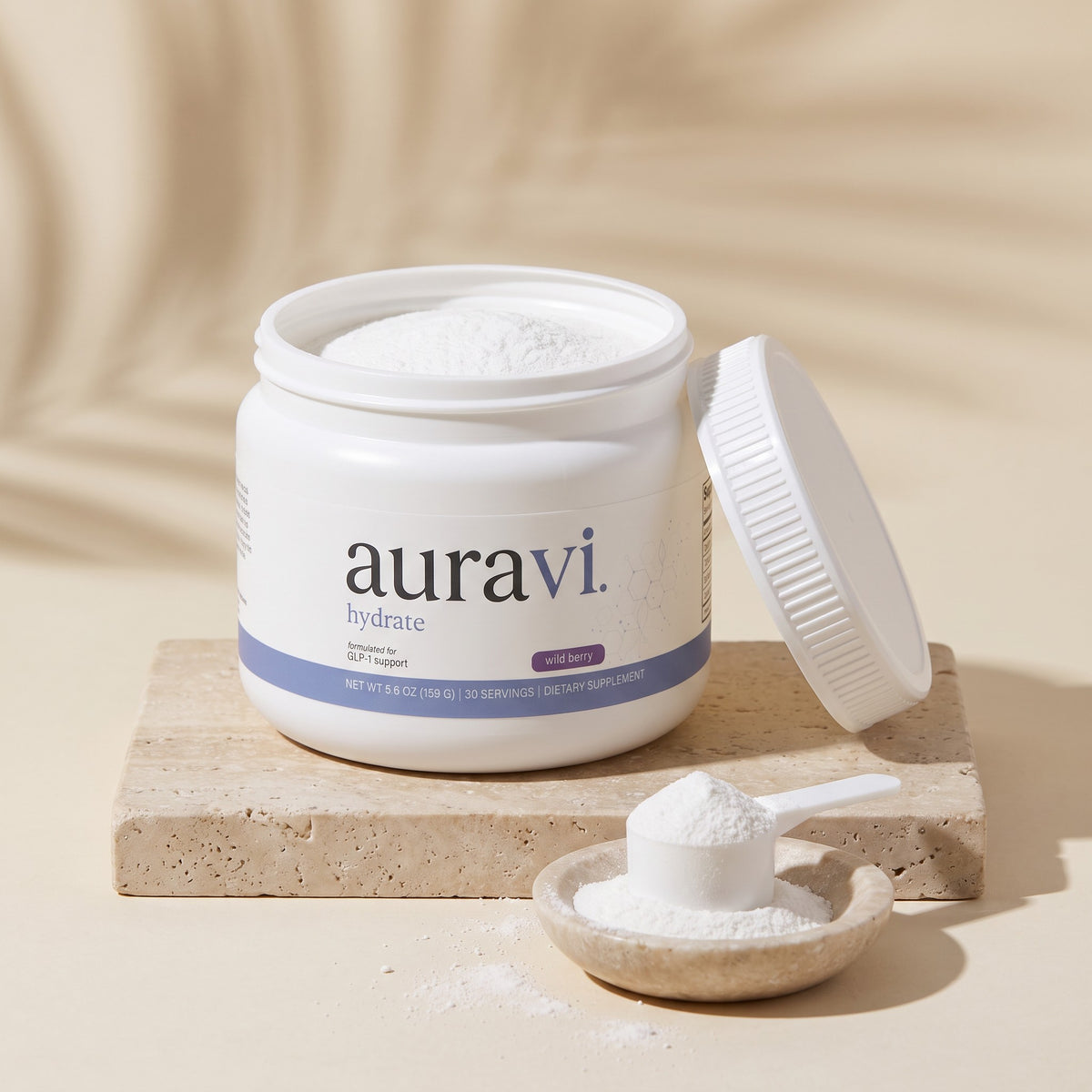 Open tub of Hydrate with a scoop of white powder on travertine